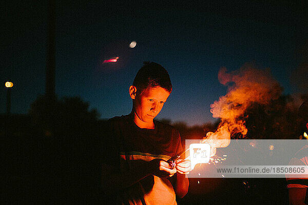 Boy holds a fire sparkler on July 4th in the dark night