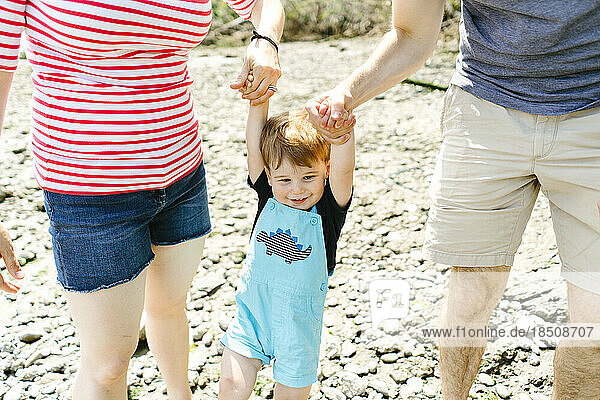 Closeup of a young toddler boy holding hands with his parents