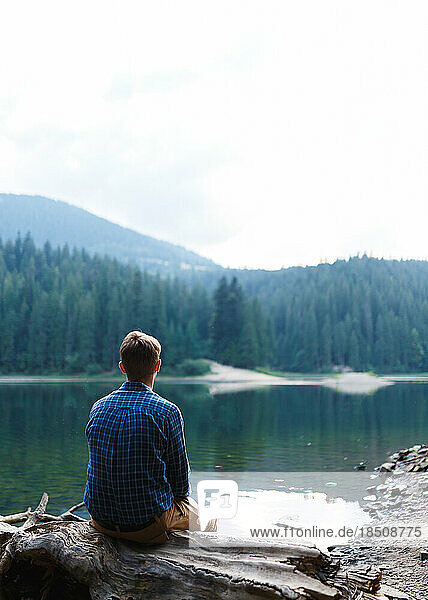 young man is alone near a mountain forest lake