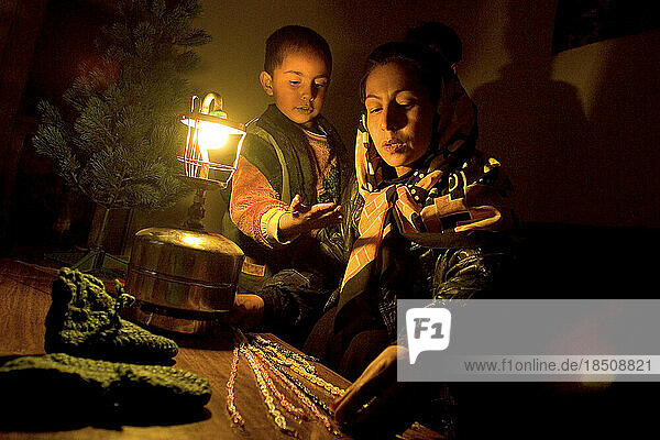 Woman and her son work by gaslight on handicraft products in Kabul.