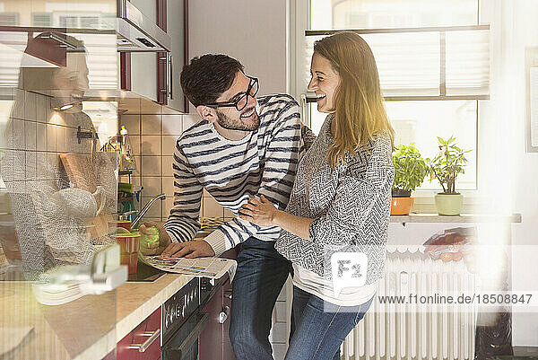 Happy couple reading newspaper in the kitchen  Munich  Germany
