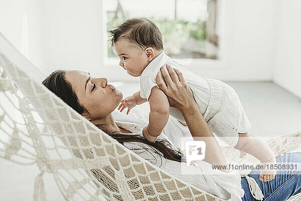 Mother and baby daughter playing in hammock in natural light studio