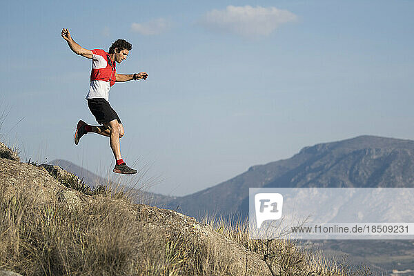 Athletic man jumping over mountains while trail running with a at a desertic location in El Arenal  Hidalgo  Mexico.
