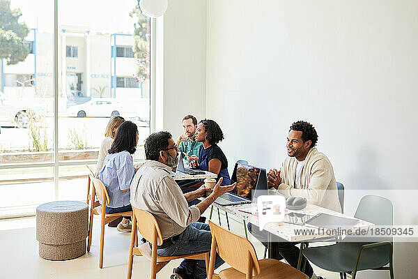 Multiracial colleagues discussing while sitting in coffee shop