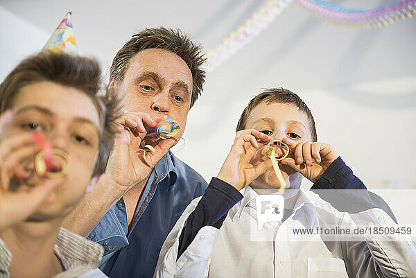 Father and son blowing paper streamers at a party