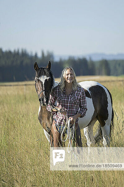 Mid adult woman standing with her horse on meadow and smiling  Bavaria  Germany