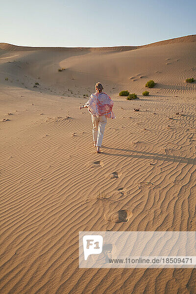 Happy woman walks in the desert during a safari. Vertical shot.