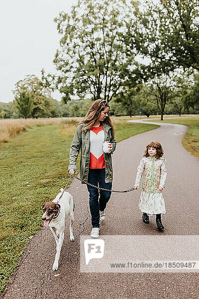 A mother and daughters walk their family dog along walking path