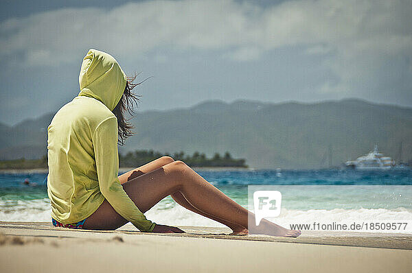 Teenage girl sitting on the beach.