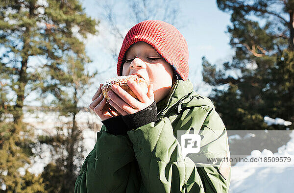 boy eating a Kanelbullar whilst outside in Sweden