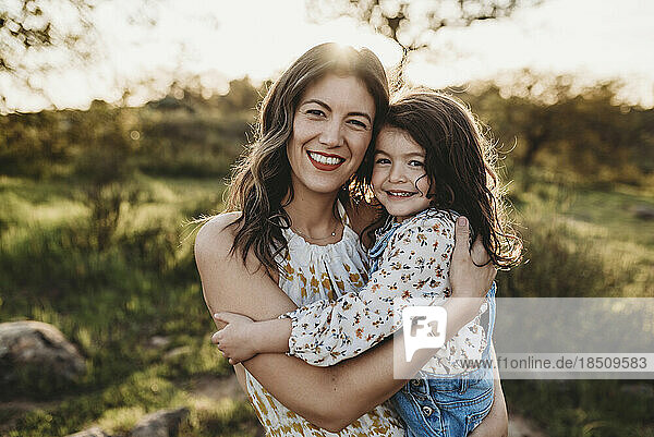 Portrait of young mother and daughter in sunny field