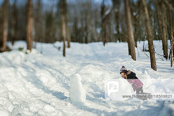 5 years old girl making a snowman on a sunny winter day
