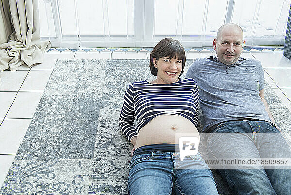 Portrait of couple lying on carpet at home