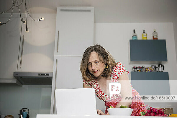 Pregnant woman using laptop for recipe in the kitchen  Munich  Bavaria  Germany