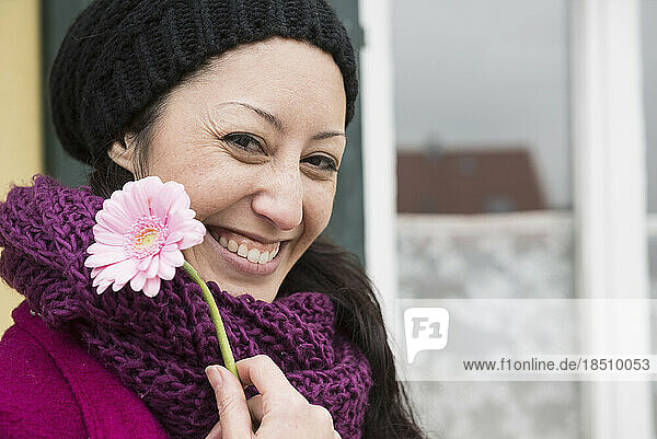 Portrait of a mid adult woman holding a pink gerbera daisy flower and smiling  Bavaria  Germany