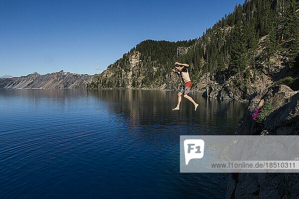 A young man jumps into the cold  clear waters of Crater Lake.