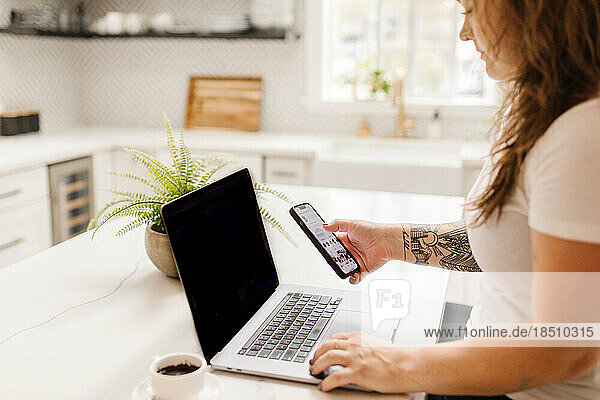 Side view of white adult woman working on computer with coffee