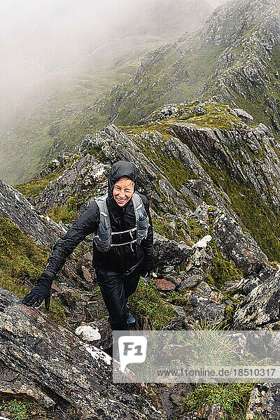 Woman hiking in rain gear on mountain ridge