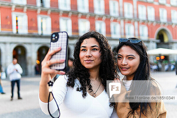 Stock photo of happy friends taking photo with phone