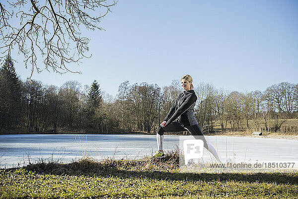 Woman doing stretching by frozen lake
