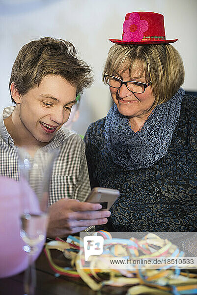 Teenager with grandmother using smartphone at party