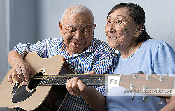 Senior man playing acoustic guitar and singing with his wife