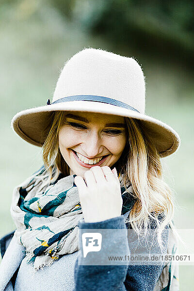Happy young woman wearing coat and hat with scarf in park