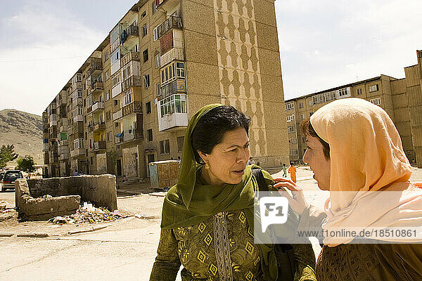 Two women walk outside apartment blocks in Kabul.