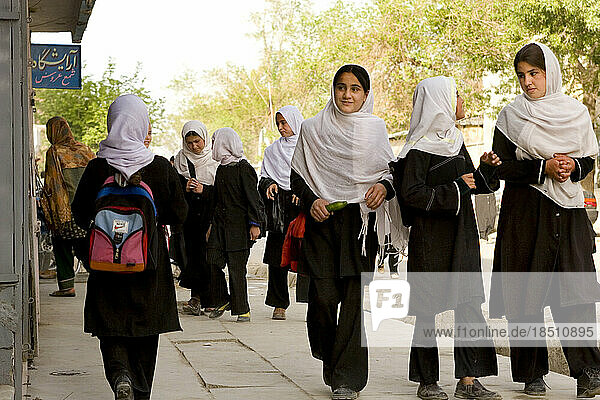 School girls in white head scarves make their way home after class in Kabul.