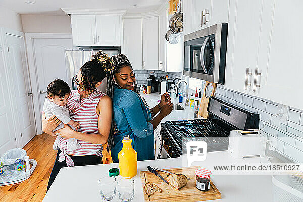 Happy lesbians enjoying with son in kitchen at home
