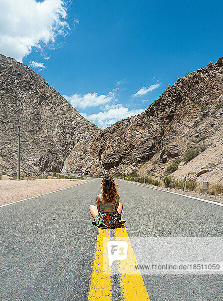 calm woman sitting looking at mountains on empty road