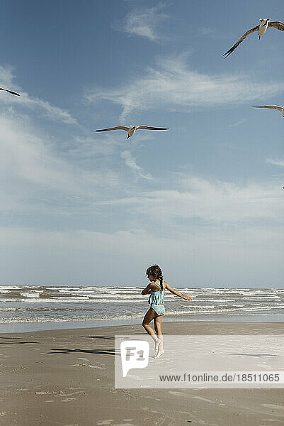 Girl twirling on beach with seagulls in Corpus Christi Texas