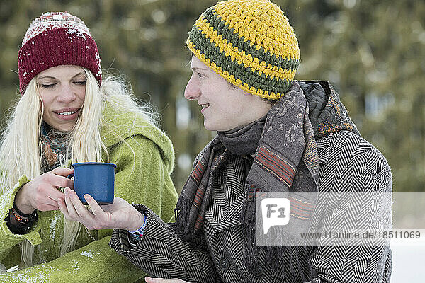 Young couple with coffee cup in snowy landscape in winter  Bavaria  Germany