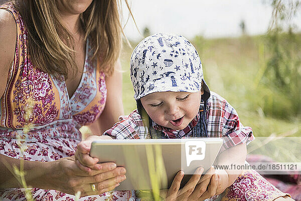 Woman using digital tablet with her little son in the countryside  Bavaria  Germany