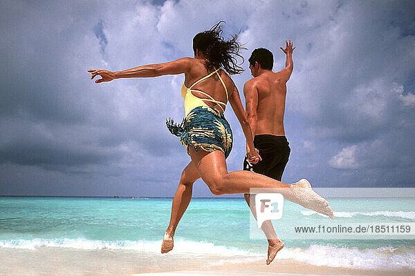 Abstract of fun couple running and jumping in Cancun on beach Mexico
