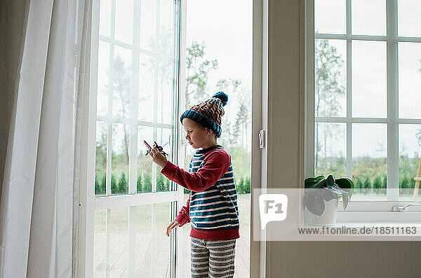 young boy playing with aeroplane in the doorway at home