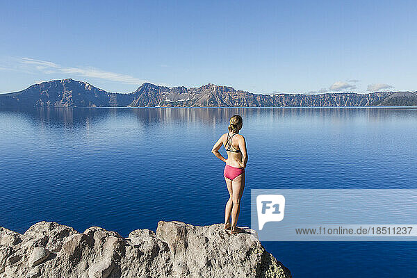 A young woman stands on the rim of Crater Lake.