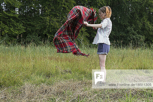 Young woman shaking blanket during camping  Bavaria  Germany
