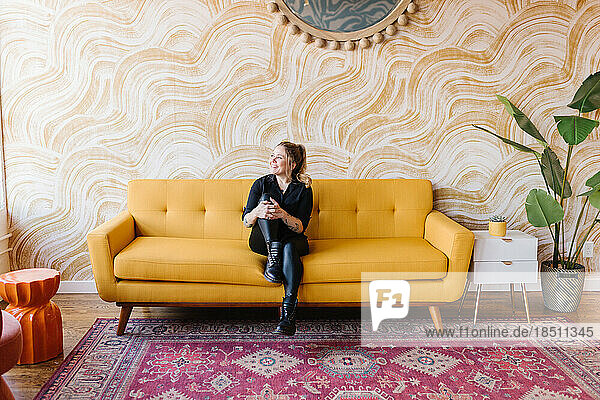Colorful vibrant room with yellow couch  woman relaxed