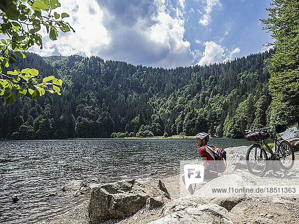 Mountain biker resting at lake Feldsee near Mt Feldberg  Baden-Württemberg  Germany