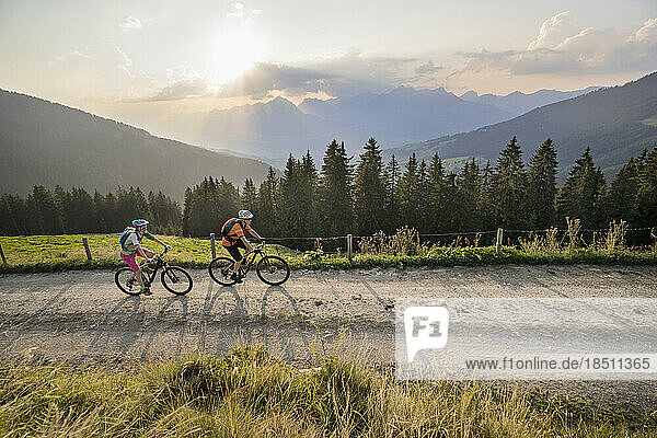Elevated view of mountain bikers riding on dirt road during sunset  Zillertal  Tyrol  Austria