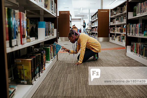 Young girl choosing book in library