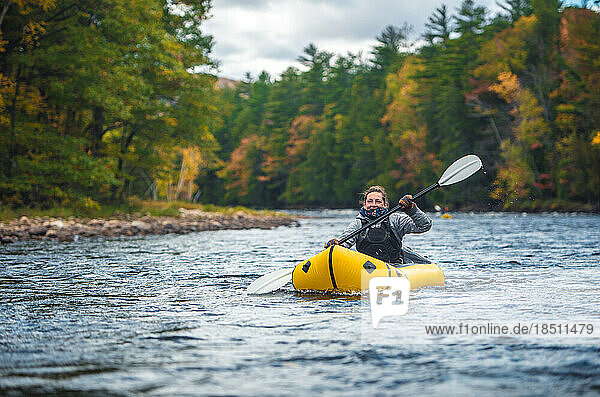 Woman smiling  laughing while paddling river in packraft
