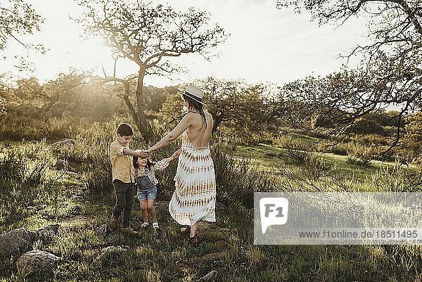 Beautiful mother and young children playing in sunny field