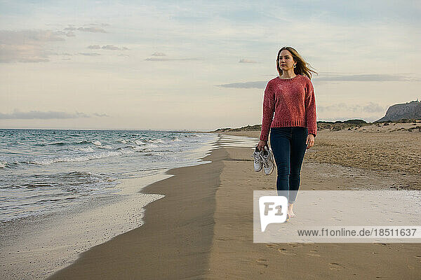 Young woman walks along the coast watching the sea