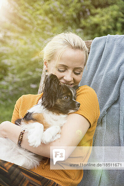 Young woman embracing dog in the domestic garden and smiling  Munich  Bavaria  Germany