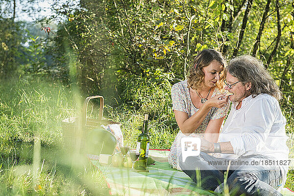 Woman feeding man with cheese on meadow  Germany