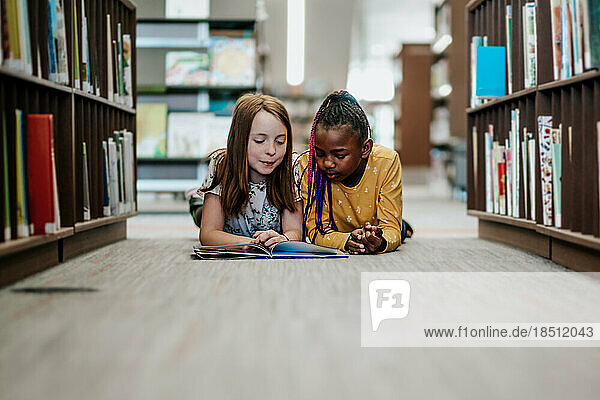 Young girls reading a library book together inside