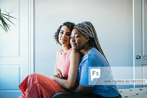 Portrait of confident lesbian couple sitting in bedroom at home