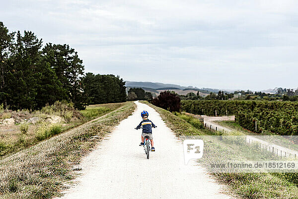 Young boy riding a bike on remote path in New Zealand